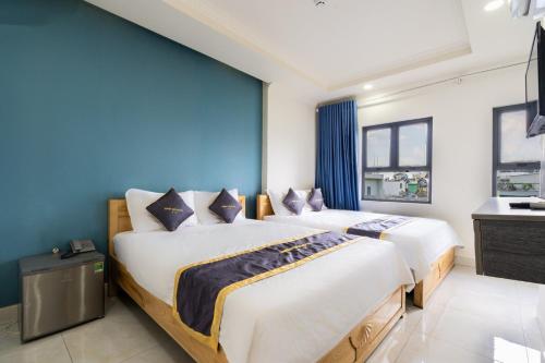 two beds in a room with blue walls at MINH THƯ HOTEL in Ho Chi Minh City