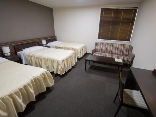a room with two beds and a chair and a table at Misato Town Community Lodge Wakuasu in Daisen