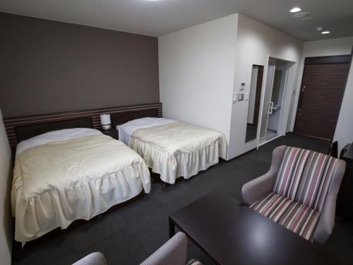 una camera d'albergo con due letti e una sedia di Misato Town Community Lodge Wakuasu a Daisen