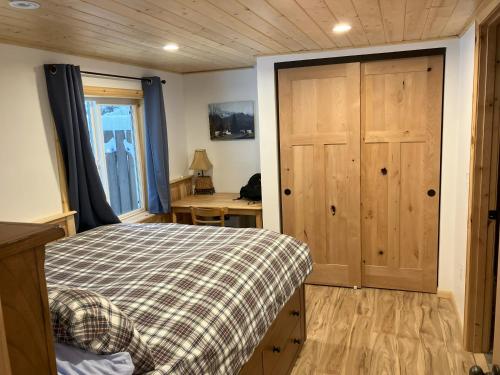1 dormitorio con 1 cama y puerta de madera en Two Lakes Guesthouse, en Seward