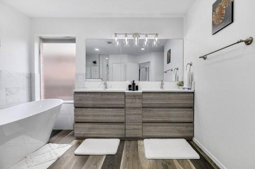 uma casa de banho com uma banheira, um lavatório e um espelho. em Frisco Resort Style Home w/Spa em Frisco