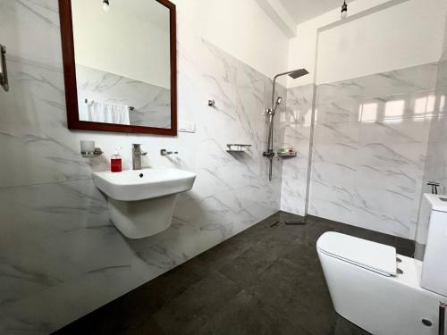 a white bathroom with a sink and a mirror at Lum Residence in Ahangama