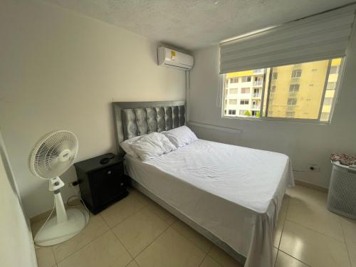 een slaapkamer met een bed, een ventilator en een raam bij Cómodo paramento zona norte in Barranquilla
