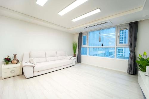sala de estar con sofá blanco y ventana en Haeundae Chocho house stay 1, en Busan