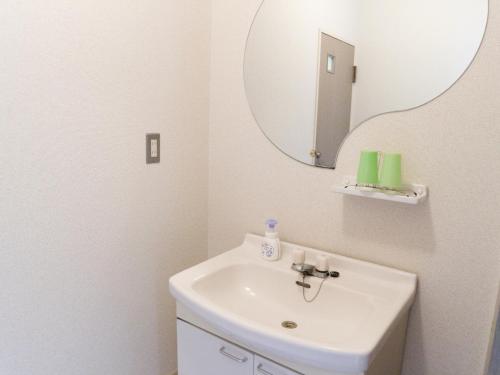 a white bathroom with a sink and a mirror at Attakayama Onsen in Rokugō