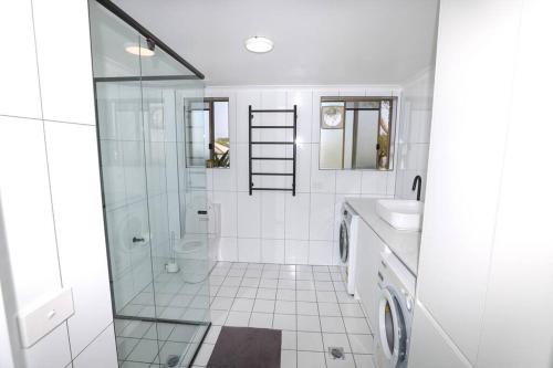 a white bathroom with a shower and a sink at Modern Retro Retreat in Tuncurry