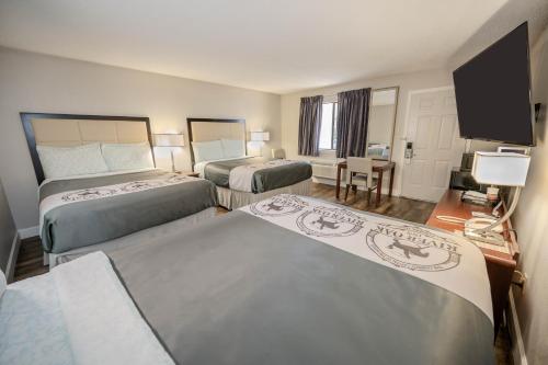 a hotel room with two beds and a flat screen tv at RIVER OAK INN in Bandera