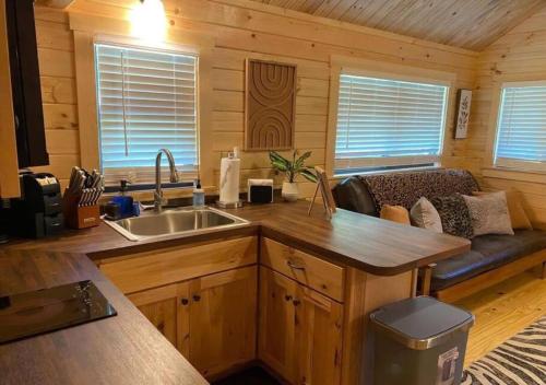a kitchen with a couch in a log cabin at Serene 1BR Cabin near NC Z00 with Loft & Waterview in Asheboro