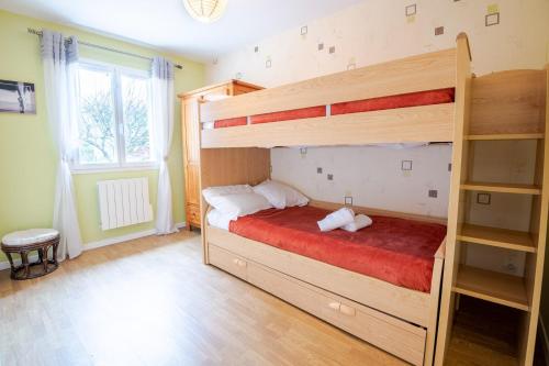 um quarto com um beliche e uma colcha vermelha em Le Sapin Parasol - Maison pour 7 pers. em Lussault-sur-Loire