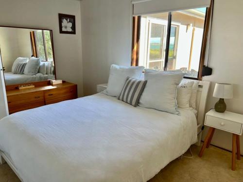 a bedroom with a white bed and a large mirror at C4 Miles Beach Shack in Robe