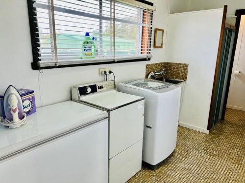 a small kitchen with a washing machine and a window at Just A Glimpse in Robe