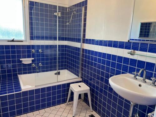 a blue tiled bathroom with a tub and a sink at Robey - Robe in Robe