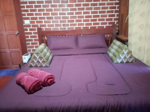 a bed with purple sheets and pillows on it at Lanta Yoky bangalow in Phra Ae beach