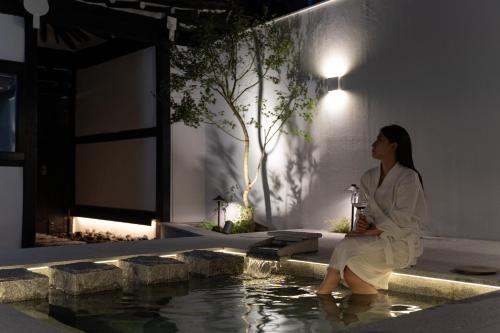 a woman in a robe sitting next to a swimming pool at Yeojuhyeon in Daegu