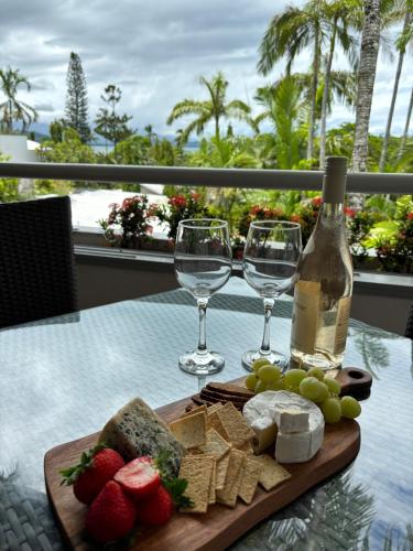 a table with a plate of cheese and wine glasses at Bella Vista in Port Douglas