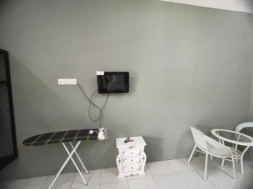 Habitación con mesa y TV en la pared. en ROOMSTAY BIENA SANA, en Pekan