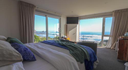 a bedroom with a bed with a view of the ocean at View With A Room NZ - Boutique Beachfront Accommodation on the Great Coast Road in Runanga