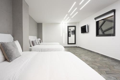 a white bedroom with two beds and a mirror at Prixma Hotel in San Andrés