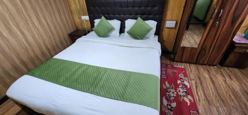 a bed with green and white sheets and pillows at Veronica Alpina Mountain View Home in Darjeeling