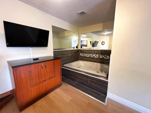 a bathroom with a tub and a tv on a wall at Riviera Inn And Suites 1000 Islands in Gananoque