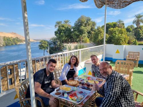 un grupo de personas sentadas alrededor de una mesa con comida en ABAZIDO Nubian Guest House en Asuán