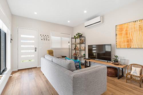 a living room with a couch and a flat screen tv at Beachside Townhouse in Rosebud
