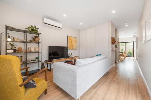 a living room with a couch and a tv at Beachside Townhouse in Rosebud