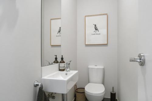 a white bathroom with a toilet and a sink at Beachside Townhouse in Rosebud