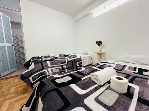 ein schwarzes und weißes Bett in einem weißen Zimmer in der Unterkunft Yerupaja Mountain Hostel in Huaraz