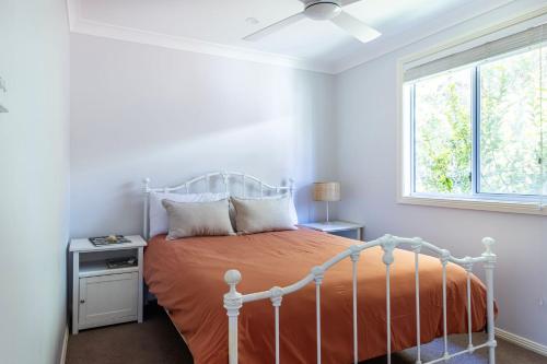 a bedroom with a bed with an orange bedspread and a window at Salt in Berrara