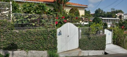 a white fence with a white gate in front of a house at SWEET PARADISE STUDIO à 10 mn du centre en voiture in Fort-de-France