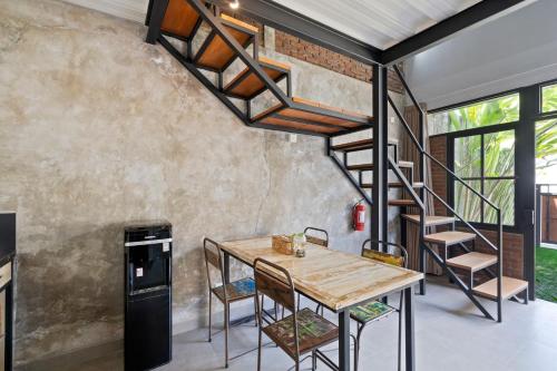 a room with a wooden table and a spiral staircase at Ambara U6 Loft by Hombali in Canggu