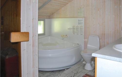 a bathroom with a white tub and a toilet at Awesome Home In Hejls With 4 Bedrooms, Sauna And Wifi in Hejls