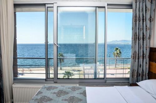 a bedroom with a large window with a view of the ocean at Perla Hotel in Dikili