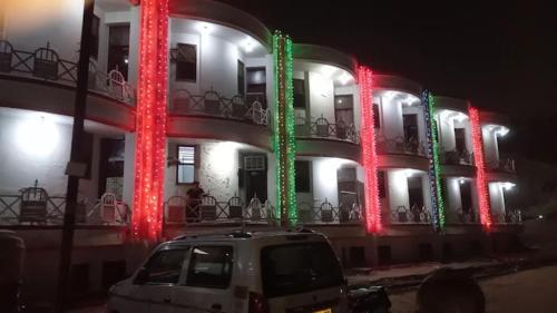 een wit busje geparkeerd voor een gebouw met rode en groene lichten bij Hotel Taj Palace Agra in Agra