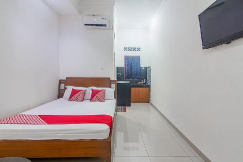 um quarto com uma cama e uma televisão de ecrã plano em OYO 93691 Minongga em Jakarta