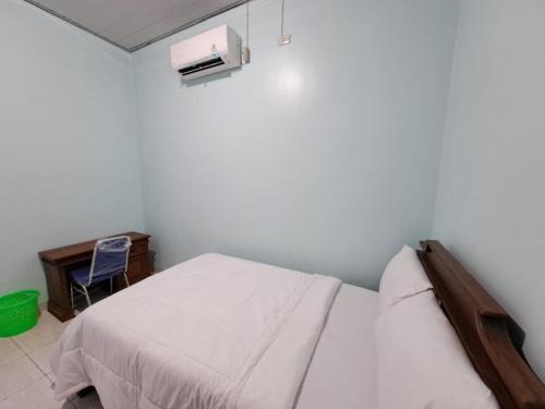 a small bedroom with a bed and a desk at OYO 93695 Guest House Riharti Syariah in Bandar Lampung