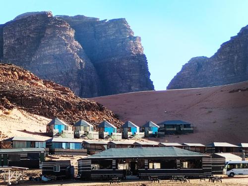 um grupo de cabanas no deserto perto de uma montanha em rum guest house em Wadi Rum