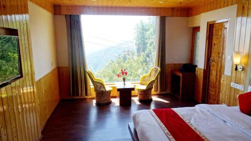 sypialnia z łóżkiem i dużym oknem w obiekcie Humble Holiday Inn Kufri Simla w mieście Shimla