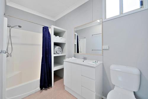 a white bathroom with a toilet and a sink at Ned Kelly's Motel in Maryborough