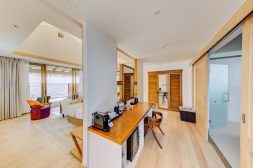 a living room with a kitchen and a living room at Cinnamon Hakuraa Huraa Maldives - All Inclusive in Meemu Atoll