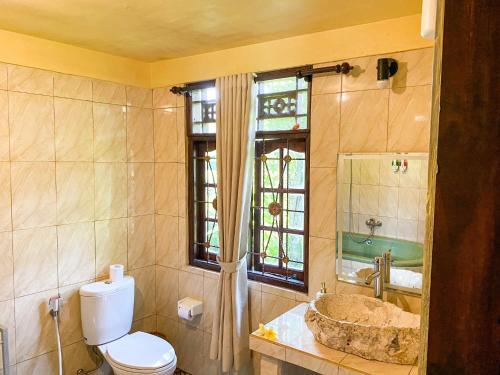 a bathroom with a toilet and a sink and a window at Atres Villa in Munduk