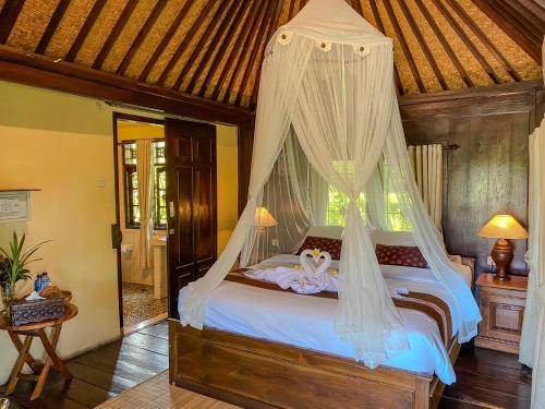 a bedroom with a bed with a mosquito net at Atres Villa in Munduk