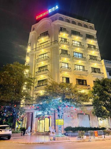 um edifício de hotel com uma árvore em frente em DOMINIC HOTEL em Hòa Ðình