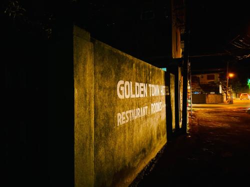 un panneau sur le côté d'un mur la nuit dans l'établissement Golden Town Hotel, à Tangalle
