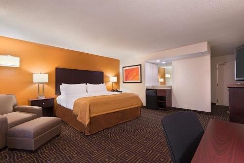 ノックスビルにあるHoliday Inn Knoxville West - Cedar Bluff, an IHG Hotelのベッドと椅子が備わる広いホテルルームです。