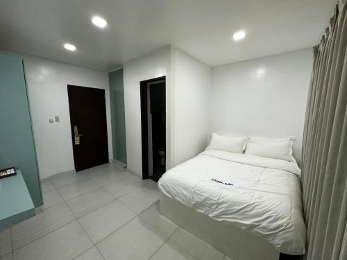 a bedroom with a bed with white sheets and pillows at Luckytito Anilao Resort in Mabini