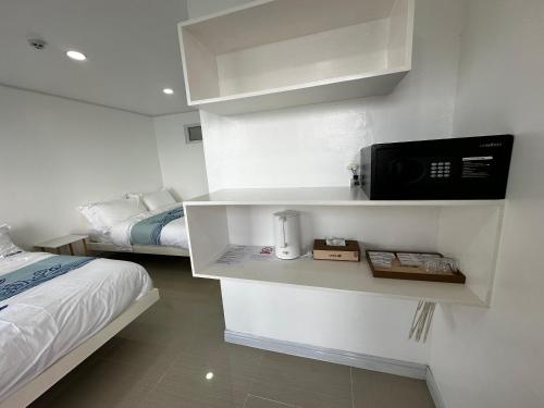 a small room with a bed and a microwave at Luckytito Anilao Resort in Mabini