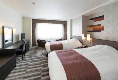 a hotel room with two beds and a television at Grand Mercure Ise-shima Resort & Spa in Shima