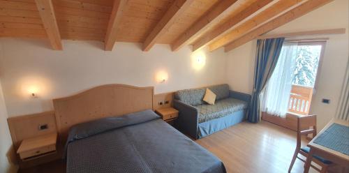 a bedroom with a bed and a couch and a window at Appartamento da Meto in San Martino di Castrozza